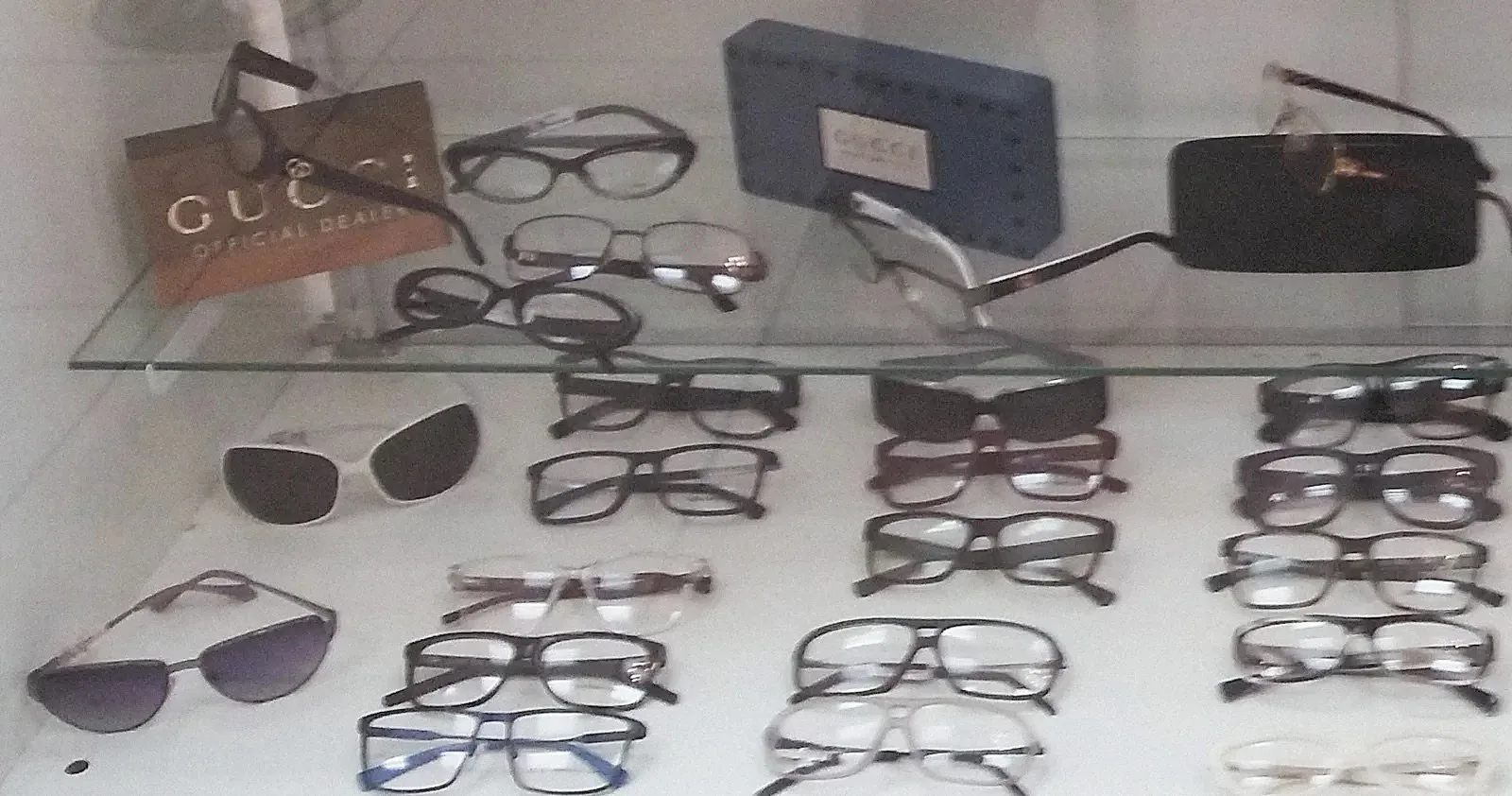 Gafas de sol y monturas en una repisa de cristal con el letrero de Gucci